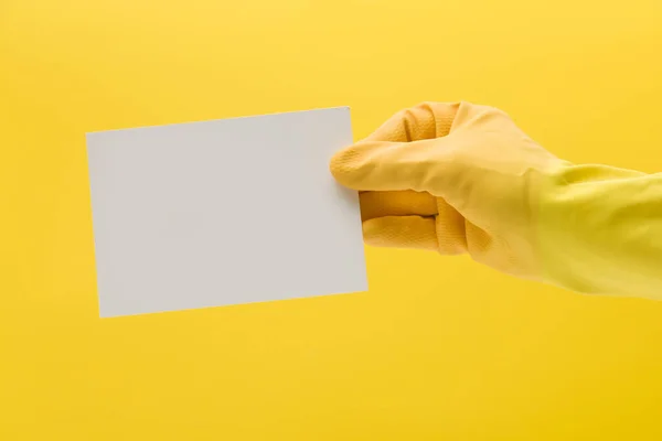 Handen i en gul rengöringshandske som håller ett tomt vitt kort — Stockfoto