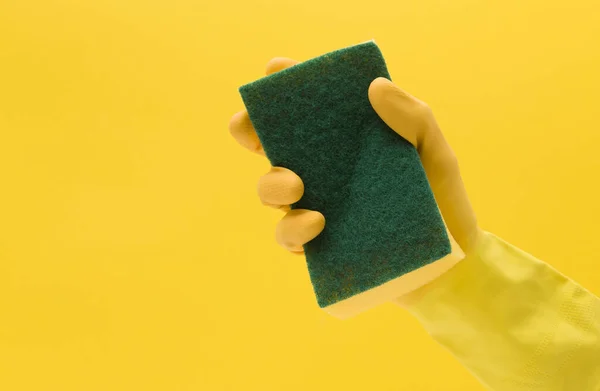 Mano con un guante de goma amarillo sosteniendo una esponja de limpieza — Foto de Stock