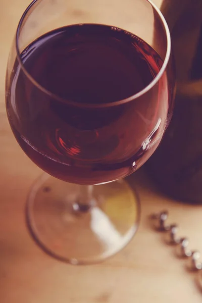 Copa de vino tinto con una botella sobre un fondo de madera — Foto de Stock