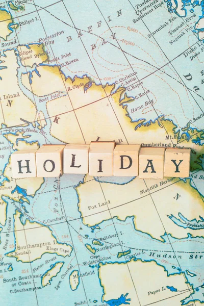 Holiday word written in wooden blocks on a vintage travel map — Stock Photo, Image