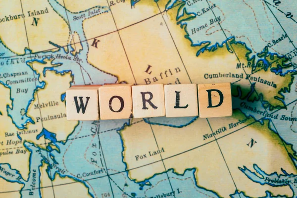Wereld woord geschreven in houten blokken op een vintage reiskaart — Stockfoto