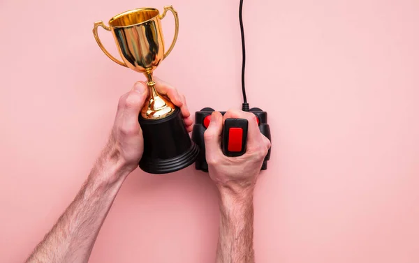 winning gamer. Hand using a retro games joystick with a gold winning trophy
