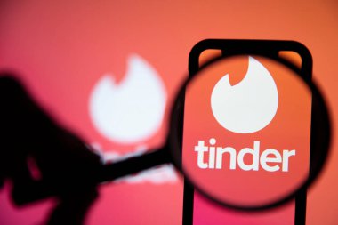 LONDON, İngiltere - 29 Nisan 2020: Büyüteç altında Tinder randevu uygulaması logosu