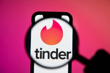 LONDON, İngiltere - 29 Nisan 2020: Büyüteç altında Tinder randevu uygulaması logosu