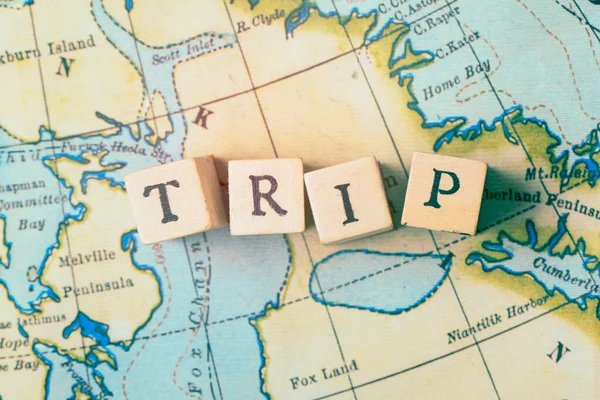 Trip word written in wooden blocks on a vintage travel map — Stock Photo, Image