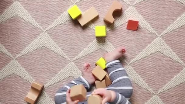 俯瞰一个小宝宝在家里玩木制积木的情景 — 图库视频影像