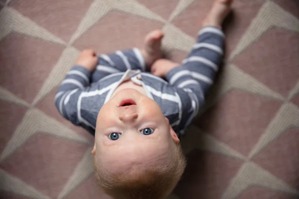 Um menino bonito sentou-se em um chão de berçário olhando para a câmera — Fotografia de Stock