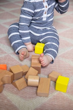 Tahta oyuncaklarla çevrili bebek bacakları ve ayak parmakları
