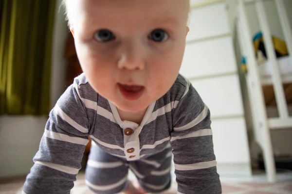 파란 줄무늬 옷을 입은 아기가 카메라를 향해 기어가는 모습을 클로즈업 한 모습 — 스톡 사진