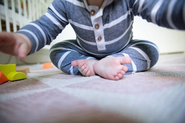 Close up de um bebê sentado no chão enquanto eles estendem a mão para a câmera — Fotografia de Stock