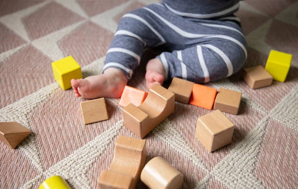Baby 's benen en tenen omgeven met houten speelgoed bouwstenen — Stockfoto