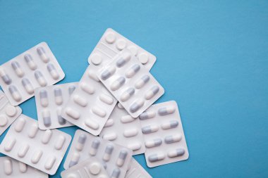 Parlak mavi arka planda ilaç ve tablet paketleri