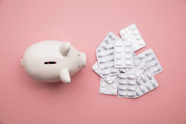 Náklady na zdravotní péči. Peněžní box prasátko banka s balíčky pilulek a tablet — Stock fotografie