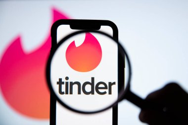 LONDON, İngiltere - 29 Nisan 2020: Büyüteç altında Tinder randevu uygulaması logosu