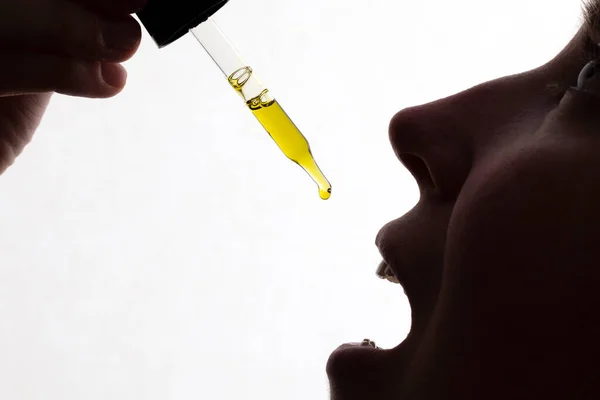 Silhouette of a woman taking drops of CDB oil — Stock Photo, Image