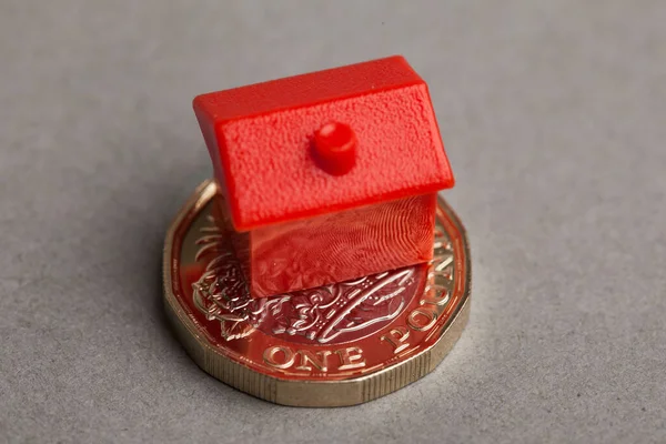 Casa roja en una moneda británica de una libra esterlina. Concepto de precio inmobiliario — Foto de Stock