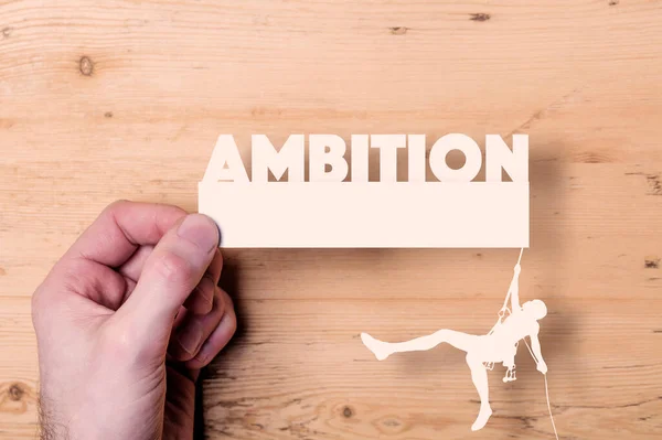 Un recorte de papel de un escalador que llega a la palabra Ambición. Concepto empresarial — Foto de Stock
