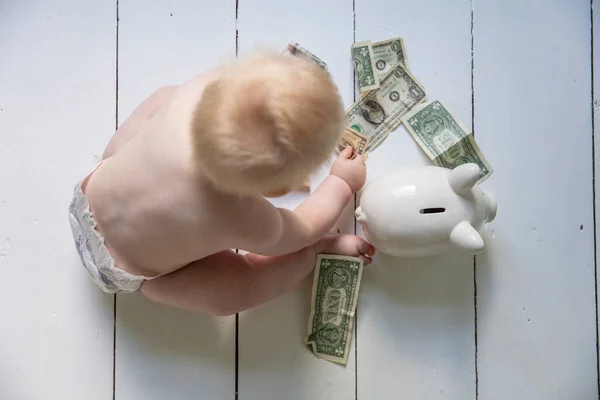 Νεαρό μωρό κάθεται στο πάτωμα βάζοντας χρήματα σε ένα κουμπαρά — Φωτογραφία Αρχείου