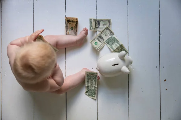 Επενδύουν στο μέλλον τους. Το μωράκι βάζει δολάρια σε έναν κουμπαρά. — Φωτογραφία Αρχείου