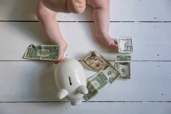 Το κόστος της παιδικής μέριμνας. Πόδια μωρού με αμερικάνικα δολάρια και κουτί χρημάτων. — Φωτογραφία Αρχείου