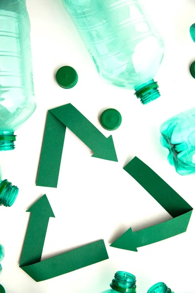 Boş plastik su şişeleriyle yeşil kağıt geri dönüşüm sembolü — Stok fotoğraf