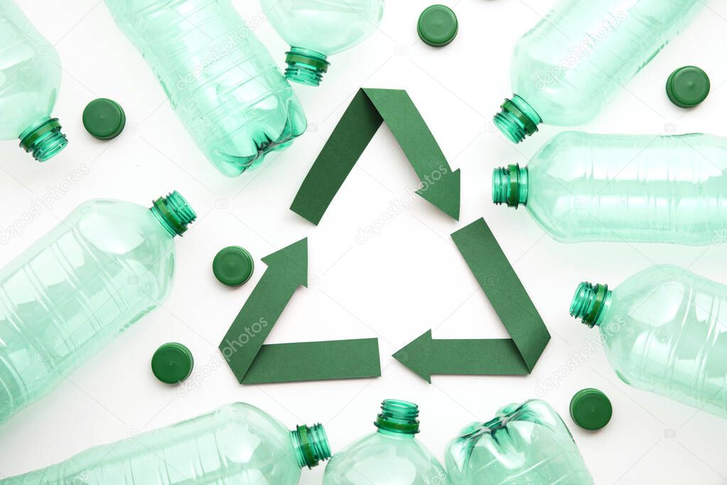 Green paper recycling symbol with empty plastic water bottles