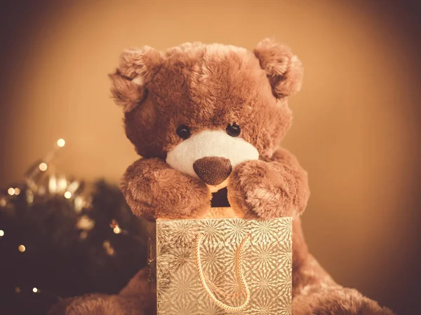 Christmas card with Teddy Bear opening gift and holiday decoration.