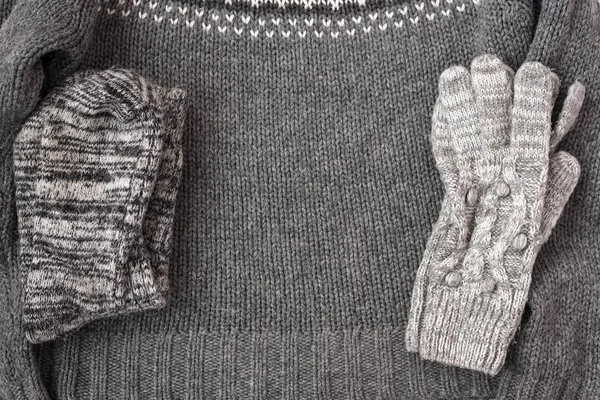 Warm female gray knitted gloves, socks on a sweater textured background. Flat lay, top view minimal fashion concept.