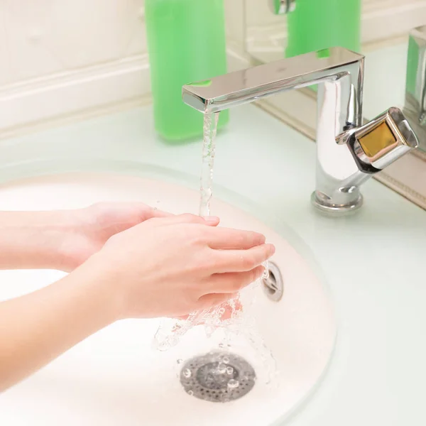 Hygiene concept. Girl washing hands with soap under the faucet with water