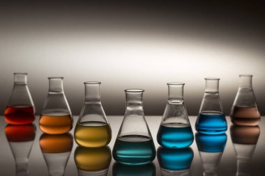 Gökkuşağı oluşturan renkli sıvılarla dolu bilimsel laboratuar camı Erlenmeyer şişesi..