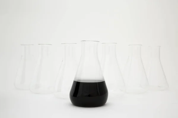 科学实验室的玻璃瓶，装有黑色液体，白色背景的玻璃器皿. — 图库照片