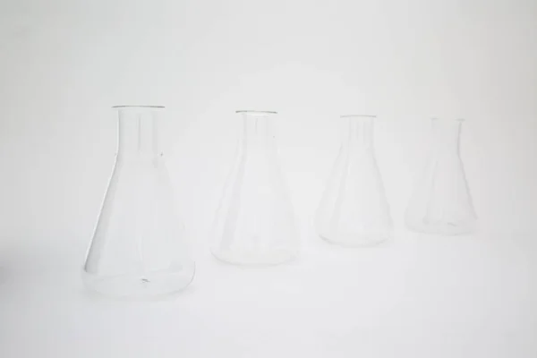 Fila de frasco erlenmeyer de vidrio de laboratorio científico aislado sobre fondo blanco —  Fotos de Stock