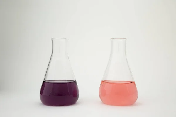 科学实验室的玻璃瓶，装有白色背景的紫色和粉色液体. — 图库照片