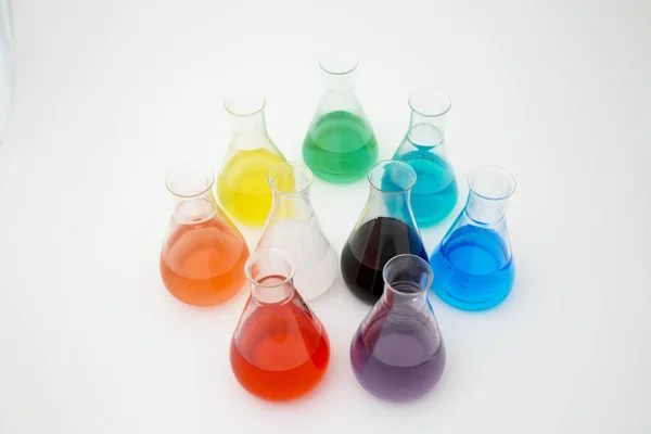 Tudományos laboratóriumi üveg erlenmeyer lombik tele színes folyadék alkotó szivárvány fehér alapon. — Stock Fotó