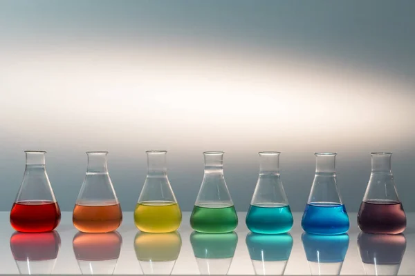 Scientific laboratory glass erlenmeyer flask filled with colorful liquid forming rainbow. — Stock Photo, Image