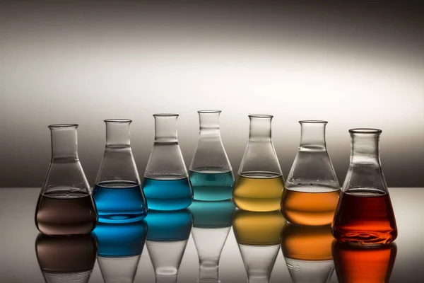 과학 실험실의 유리 렌즈 플라스크에 다채 로운 액체로 가득 차 있고 무지개를 이루고 있다. — 스톡 사진
