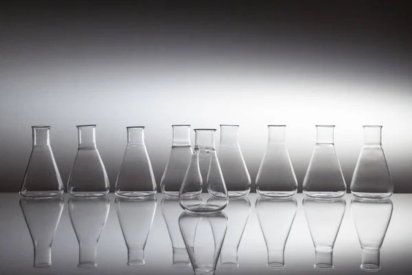 Yansıtıcı yüzeyde bir grup bilimsel cam Erlenmeyer cam şişe ekipmanı.. — Stok fotoğraf