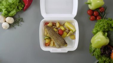Köpük kutusunda paket yiyecek paketliyorum. Balık ve patatesli taze paket yemek.