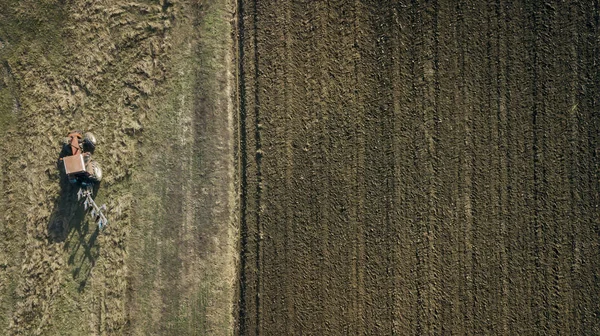 Panoramische Luftaufnahme eines landwirtschaftlich bewirtschafteten Feldes mit Traktor, der Herbstbearbeitung durchführt — Stockfoto