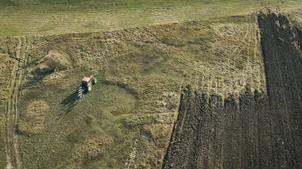 Panoramische Luftaufnahme eines landwirtschaftlich bewirtschafteten Feldes mit Traktor, der Herbstbearbeitung durchführt. — Stockfoto