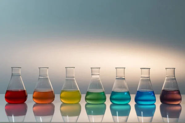 Scientific laboratory glass erlenmeyer flask filled with colorful liquid forming rainbow. — Stock Photo, Image