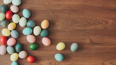 Colorful Easter eggs rolling on wooden table. Easter holiday decorations, Easter concept background.