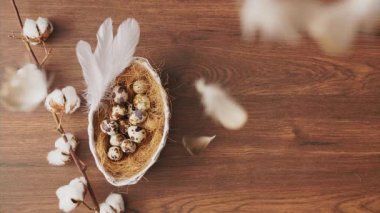 Feathers falling on Easter eggs in nest on wooden table. Easter holiday decorations, Easter concept background.