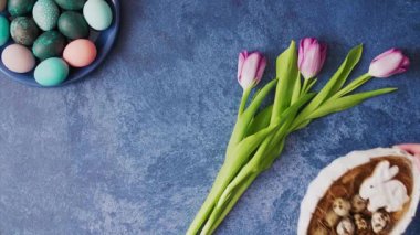 Hands putting down basket with Colorful Easter eggs on deep blue background. Easter holiday decorations , Easter concept background.