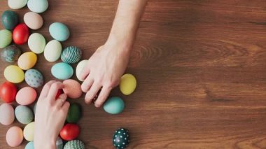 Hands Taking colorful Easter eggs of wooden table. Easter holiday decorations, Easter concept background.