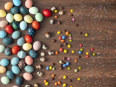 Ahşap masada renkli Paskalya yumurtaları ve şekerlerle. Paskalya bayramı süslemeleri, Paskalya konsepti.