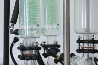 Rotavapor adı verilen rotasyonel buharlaştırıcı modern laboratuardaki masanın üzerine yerleştirilmiş yeşil yoğunlaştırıcı. CBD özetleri Erlenmeyer şişelerinde masanın üzerinde. Esrar eczacılık sağlık hizmetleri süreci.