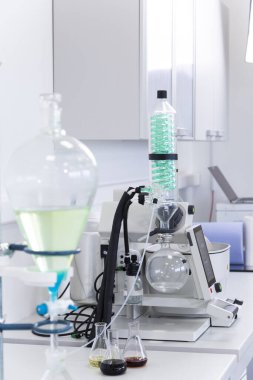Rotavapor adı verilen rotasyonel buharlaştırıcı modern laboratuardaki masanın üzerine yerleştirilmiş yeşil yoğunlaştırıcı. CBD özetleri Erlenmeyer şişelerinde masanın üzerinde. Esrar eczacılık sağlık hizmetleri süreci.