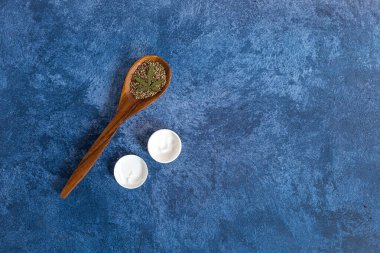 Esrar vücut kremi ve kenevir tohumları koyu mavi arka planda. Kozmetikte tıbbi marihuana.