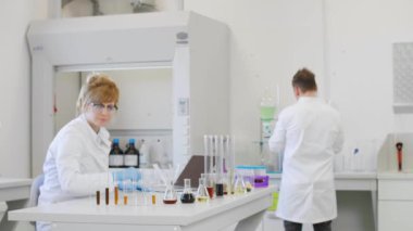Laboratuvarda kenevir CBD ve CBDA yağlarıyla çalışan kimya bilimcisi. Sonuçları dizüstü bilgisayarında yazıyor, cam tüpler ve erlenmeyer mataraları kullanıyor. Esrar tohumlarından alınan sağlık hizmetleri eczanesi.